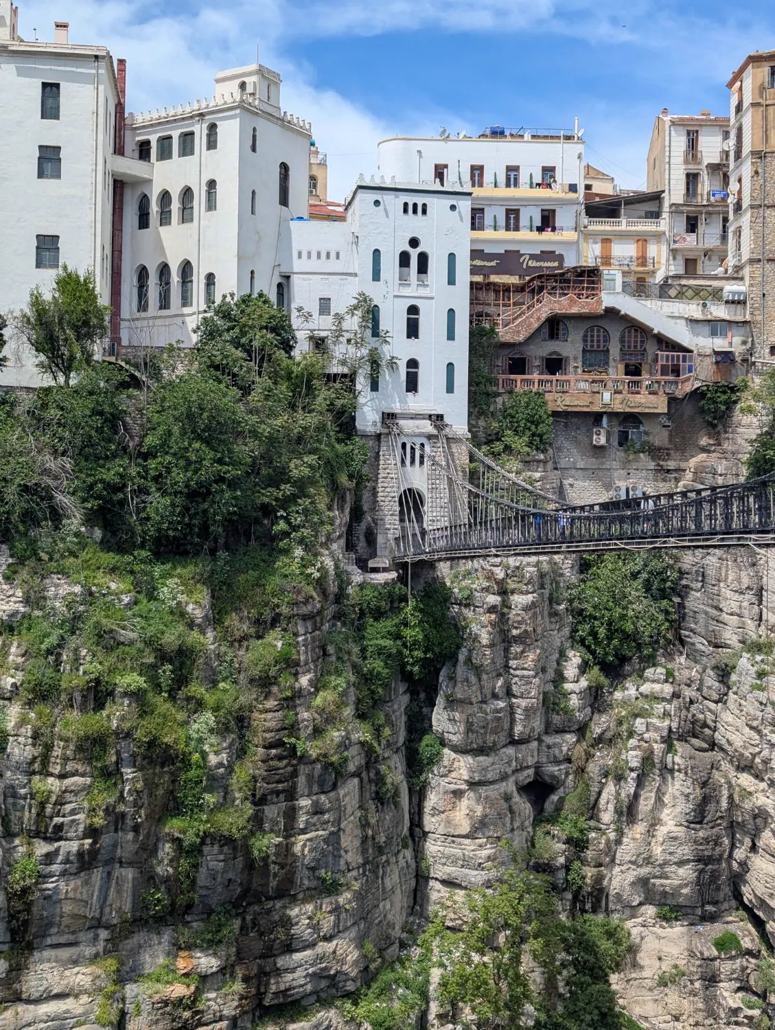 White houses perched on the cliff above a footbridge