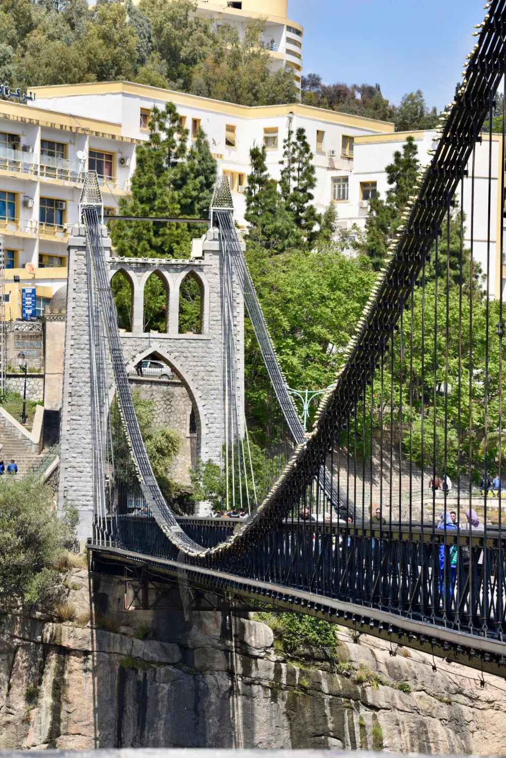 Walkers crossing the stone tower of a suspension bridge
